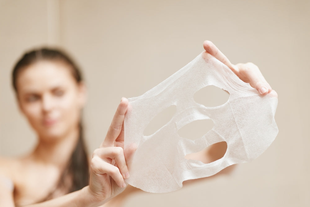 Woman holding a sheet mask against a neutral background. CICA & SEA GRAPE (Caulerpa Lentillifera) EXTRACT Mask 